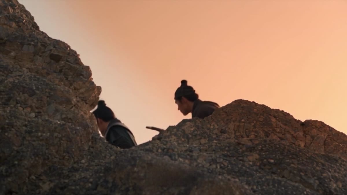 夕照下，山道岩石后的人物准备伏击的成片画面